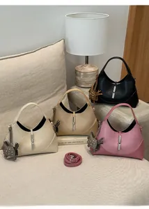 Detail view of crescent shoulder bags in black, beige and pink with metal buckle and tassels