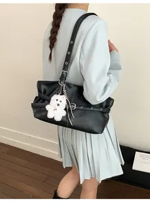 Détail du sac à bandoulière noir en similicuir plissé avec sangle et breloque ours