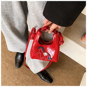 Detailed view of red mini crossbody bag with horse embroidery and quilted pattern on outfit