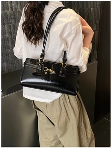 Detail of glossy black patent leather shoulder bag with elegant gold-tone hardware