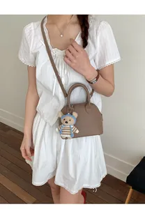 Brown lychee leather shell bag detail with a cute bear charm and thin shoulder strap