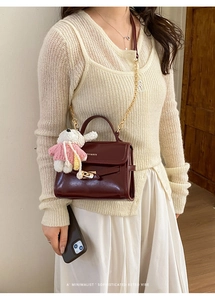 Close-up of wine red bucket bag with gold chain strap and cute plush bunny charm