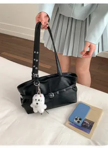 Détail du sac cabas en similicuir noir avec œillets argentés et pendentif peluche blanc