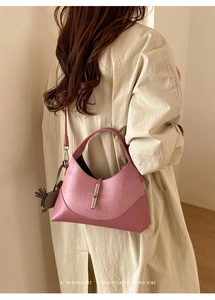Macro detail of pink pebbled leather hobo bag with piston clasp and grey tassel charm