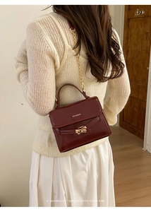 Detail view of a retro dark red bucket bag with gold chain strap and metal lock