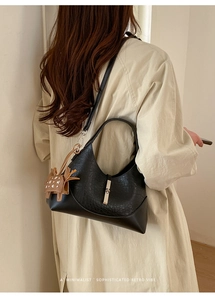 Close-up of black leather bucket bag with gold lock and brown horse charm accessory