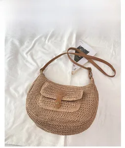 Détail du sac selle tissé montrant la boucle en cuir et la texture de paille kaki