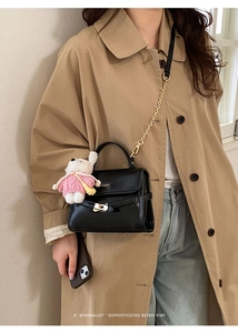 Detail of black crossbody bag with gold turn-lock and cute bunny plush charm