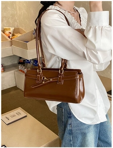 Detailed view of dark brown glossy leather vintage shoulder bag with metal buckle design