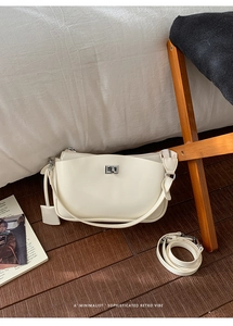 Detail der cremeweißen PU-Ledertasche mit silbernem Drehverschluss und verstellbarem Gurt