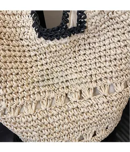 Detail of hollow woven straw bag showing beige texture and black trim craftsmanship