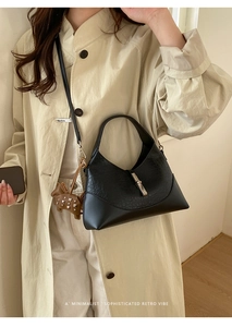 Detail of retro black bucket bag featuring silver cylinder buckle and brown horse charm