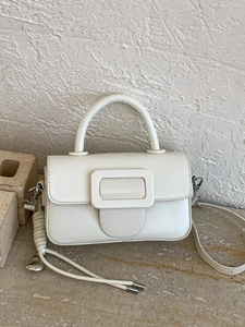 Borsa a mano bianca minimalista con maxi fibbia quadrata su sfondo di pietra naturale