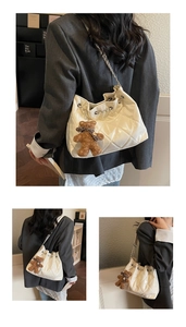 Detail view of white quilted bucket bag with silver chain strap and plush bear charm