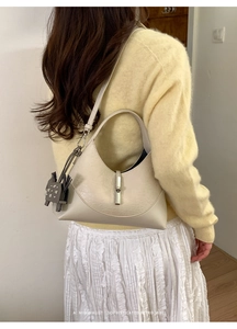 Close-up of cream hobo bag with a stylish grey dog charm on a soft knit background