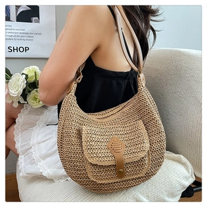 Détail macro du sac hobo bohème en paille tressée avec rabat en cuir brun et boucle