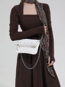 Sac à bandoulière vintage blanc avec rivets argentés et chaîne porté par un mannequin