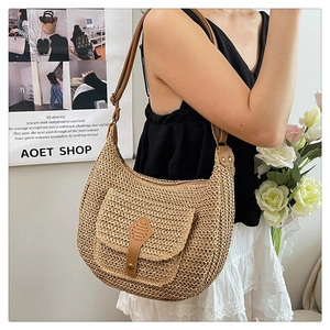 Détail du tissage en paille naturelle et de la poche en cuir sur le sac selle croissant