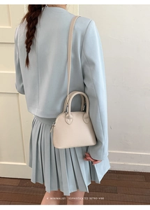 Beige shell-shaped crossbody bag with lychee texture worn with a blue blazer