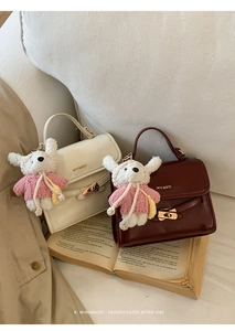 Detail of retro bucket bag with MUHETI logo, golden lock and cute bear charm pendant