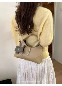 Detail of contrast bucket bag featuring silver buckle and horse charm on yellow knit