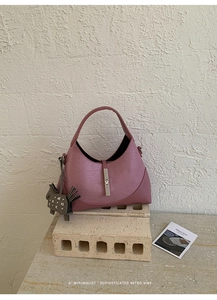 Close-up of minimalist dusty pink bag with silver magnetic clasp and animal charm