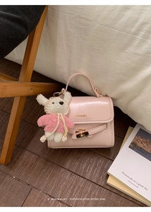 Detail of light pink crossbody bucket bag with cute bear charm on wooden floor