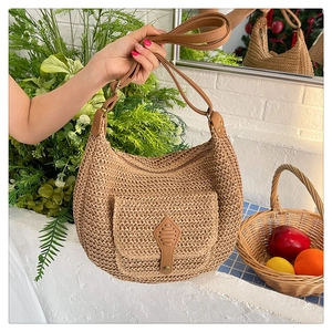 Détail du sac selle en paille tressé à la main avec bandoulière en cuir brun et boucle décor