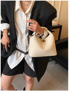 Detail of cream lychee leather bucket bag with gold lock and Moda & Bags logo