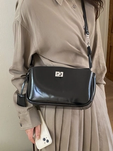 Minimalistische schwarze Schultertasche mit Silber-Drehverschluss am Model präsentiert