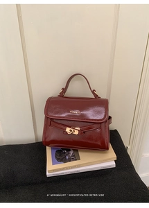 Close-up of deep red glossy leather bucket bag featuring gold metal turn-lock and handle