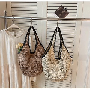 Detail of hand-woven hollow straw tote bags in brown and beige for beach vacation style