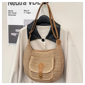 Gros plan détaillé du sac selle en paille tissée avec bandoulière en cuir PU et rabat aimanté