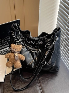 Black quilted patent leather tote bag with silver chain straps and bear charm