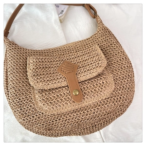 Vue détaillée du sac en paille tressée avec garniture en cuir brun et boucle en métal