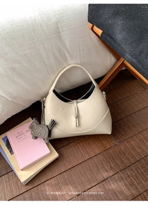 Detail of off-white crescent handbag with crocodile texture and leather horse charm