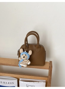 Detailed texture of brown pebble leather shell bag with cute bear charm and dual handles