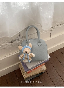 Light blue shell bag with lychee texture and cute teddy bear charm on books