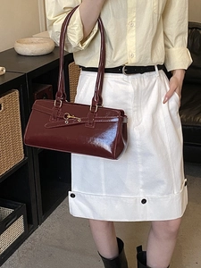 Vintage dark red glossy shoulder bag with gold hardware shown on a female model