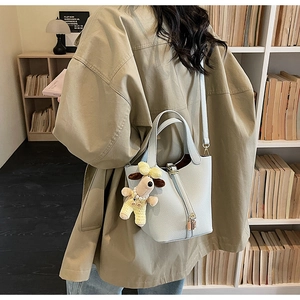Detail of light blue bucket bag in lychee leather featuring metal lock and dog charm