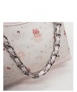 Nahaufnahme der Lederstruktur mit rosa Katzenprint und silberner Kettenriemen