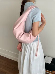 Detail of light pink crescent bag with pleated leather texture and decorative straps