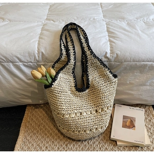 Detailed macro view of beige straw tote bag with black crochet trim and woven patterns