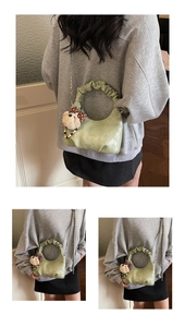 Detail of light green pleated handbag featuring a plush bear charm and chain strap