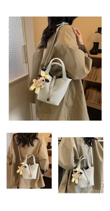 Detail view of light blue bucket bag with pebble leather and cute dog plush charm