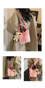 Detail of pink lychee leather bucket bag with gold lock and cute dog charm pendant