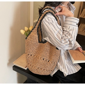 Detail of the large straw tote bag featuring black crochet edges and hollowed-out patterns