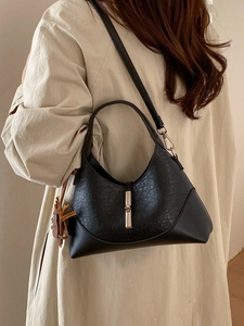 Elegant black bucket bag with vintage texture and yellow tassel on a beige coat background