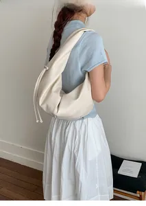 Detail of off-white dumpling bag showing matte leather texture and side drawstring accents