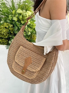 Sac hobo en paille bohème avec boucle en cuir porté par un mannequin en extérieur